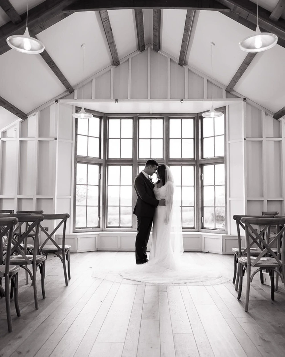 Bride and groom standing in front of large window