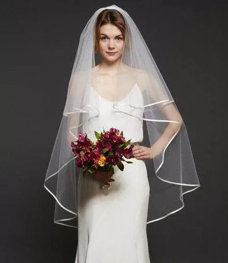 Bride wearing a waterfall ribbon edge veil in a fingertip length.