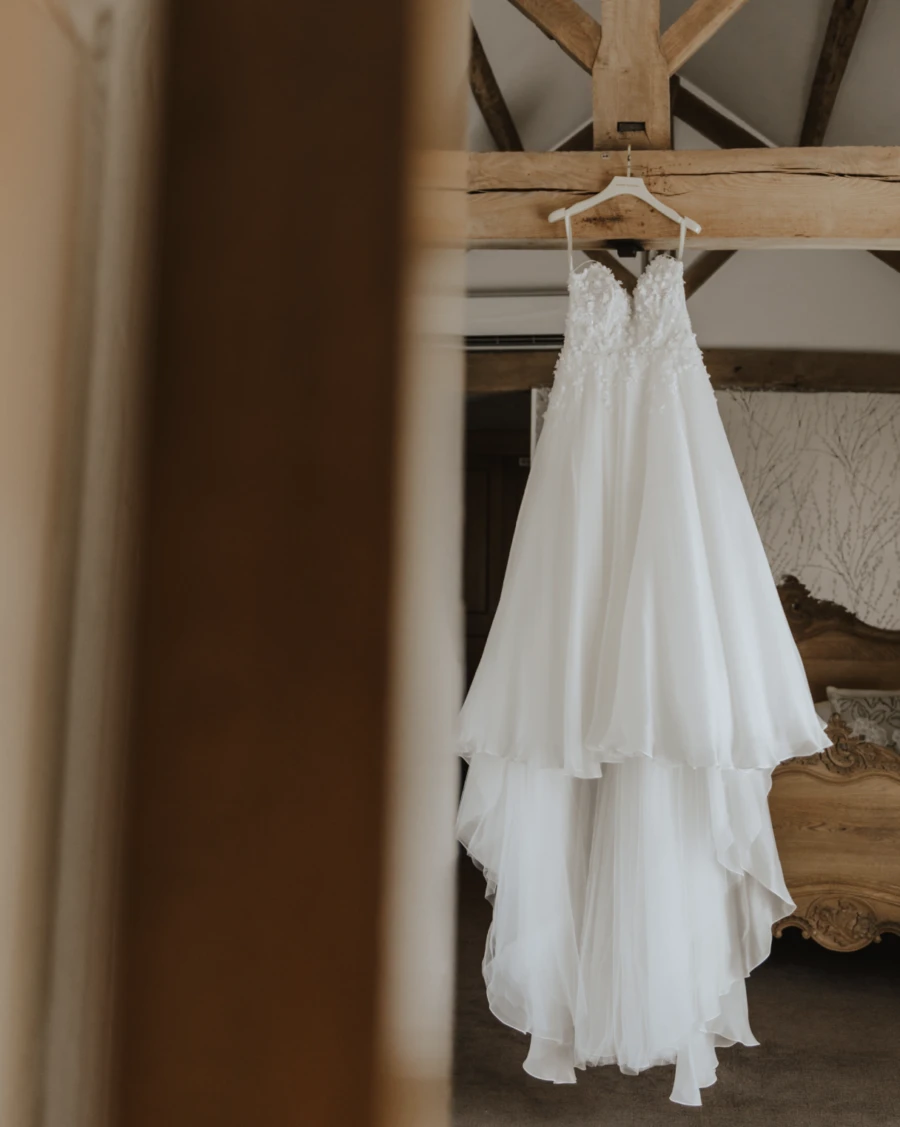 Wedding dress hanging from wooden beam