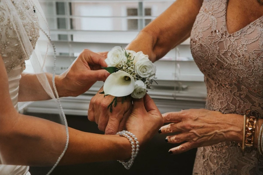 Bride putting flowers on mothers wrist